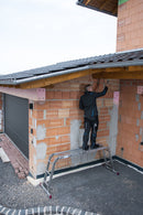 Човек работи върху къща, използвайки алуминиева стълба KRAUSE CORDA като платформа.