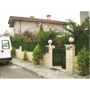 Плетена оградна мрежа с декоративно покривало около къща, обградена с храсти и жив плет.