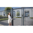 Жена отваря стилна порта с вграден затварящ автомат Interio в естетичен двор.