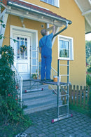 Човек използва алуминиево мобилно скеле KRAUSE за боядисване на къща, показващо безопасна работа на височина.