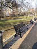 Дървена градинска пейка в парк, идеална за отдих и социализиране на открито.