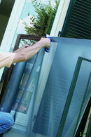 Човек монтира мрежа против насекоми Tropical на прозорец, предпазваща от комари.