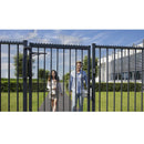 Двойка влиза през метална врата в градината с модерна архитектура на заден план.