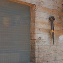 Сива мрежа против насекоми Zanzibar, поставена на дървена рамка, с инструмент облегнат до нея.